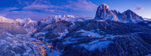Beautiful Panoramic View Of Dolomites Mountains At Dusk During Winter Time. Magical Winter Mountain Purple Sunset With A Mountain Ski Resort Village. Christmas Time.