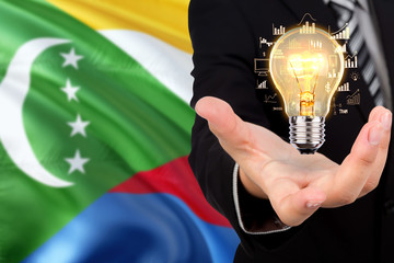 Comoros creativity concept. Businessman with a light bulb in his hand on national background. Innovation and technology theme.