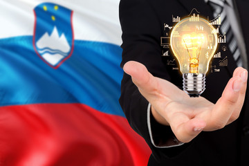 Slovenia creativity concept. Businessman with a light bulb in his hand on national background. Innovation and technology theme.