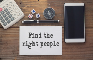 Find the right people written on paper,Wooden background desk with calculator,dice,compass,smart phone and pen.Top view conceptual.