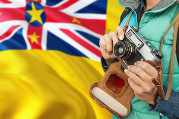 Wall Mural - Niue photographer concept. Close-up adult woman holding retro camera on national flag background. Adventure and traveler theme.