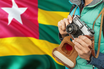 Wall Mural - Togo photographer concept. Close-up adult woman holding retro camera on national flag background. Adventure and traveler theme.