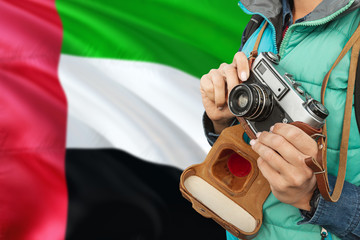 Wall Mural - United Arab Emirates photographer concept. Close-up adult woman holding retro camera on national flag background. Adventure and traveler theme.