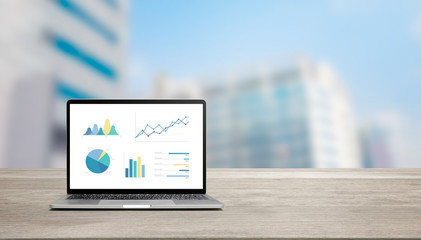 Aufkleber - modern laptop on wood table showing charts and graph against blue business building background