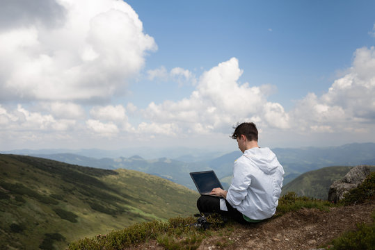 A man with a computer on top of a hill