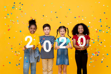  Śliczni uśmiechnięci mieszani biegowi dzieci pokazuje liczby 2020 świętuje nowego roku