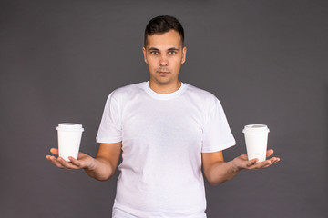 The guy in the white t-shirt is trying to choose between two types of coffee.