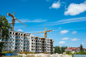 Wall Mural - Modern residential buildings under construction. Construction site with cranes on a sunny summer day