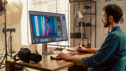 Poster - Professional Photographer Sitting at His Desk Uses Desktop Computer in a Photo Studio Retouches. After Photoshoot He Retouches Photographs of Beautiful Female Model in an Image Editing Software