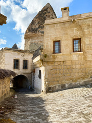 Wall Mural - Deserted street of the old turkish city. Ancient brick houses with arches and windows on a background of mountains. Cappadocia