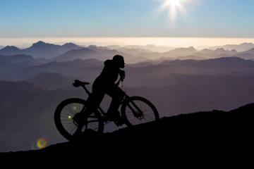 Conquering mountain peaks by cyclist in shorts and jersey on a modern carbon hardtail bike with an air suspension fork . Beautiful view from the mountain. Panoramic view for banner.	