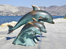 The Bronze Sculpture Of Three Dolphins On The Beach
