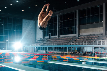 handsome swimmer diving into water in swimming pool