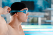 © LIGHTFIELD STUDIOS - side view of handsome swimmer in swimming cap touching goggles