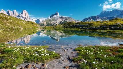 Papier Peint - Amazing Nature Landscape. Alpine lake with crystal clear water and frash grass and flowers. Perfect Blue sky and mountains peaks. Incredible view of Dolomites Alps. Tre Cime di Lavaredo National park.