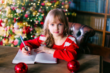 Little child writing letter to Santa at home. Christmas celebration