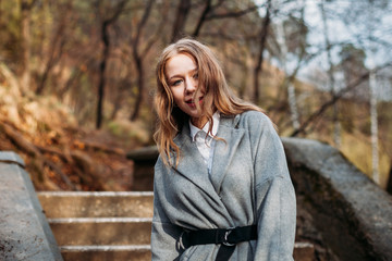 Portrait of young girl businesswoman in a grey coat posing in Park in autumn