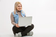 © Angelov - Young woman with laptop sitting on floor near light wall