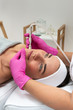 Kosmetolog wykonuje zabieg mikrodermabrazji skóry twarzy kobiety w salonie kosmetycznym. Kosmetologia i profesjonalna pielęgnacja skóry.