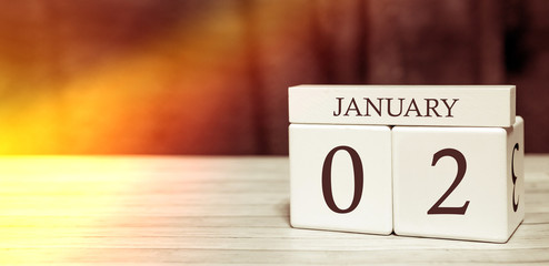 Calendar reminder event concept. Wooden cubes with numbers and month on January 2 with sunlight.