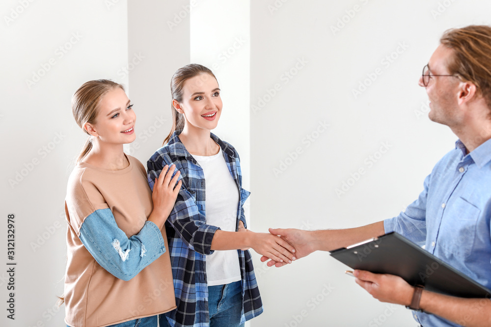 Woman shaking hands with real estate agent indoors