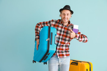 Young male tourist with luggage on color background