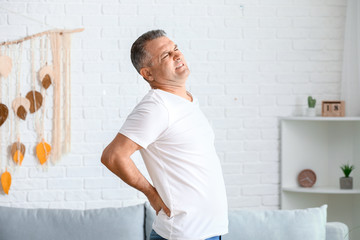 Wall Mural - Mature man suffering from back pain at home