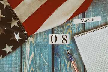 08 March calendar day Flag of the United States of America symbol of freedom and democracy with blank notepad and pen on office wooden table