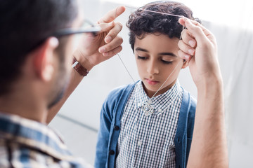 Wall Mural - cropped view of jewish father wearing star of david necklace on son in apartment