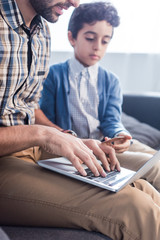 Wall Mural - cropped view of jewish father using laptop and son holding credit card in apartment