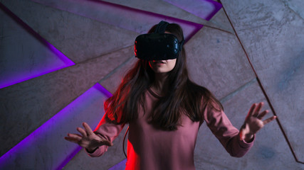 Watch out. Young woman with vr glasses and fluttering hair actively reacts, is afraid of what is happening in the game.