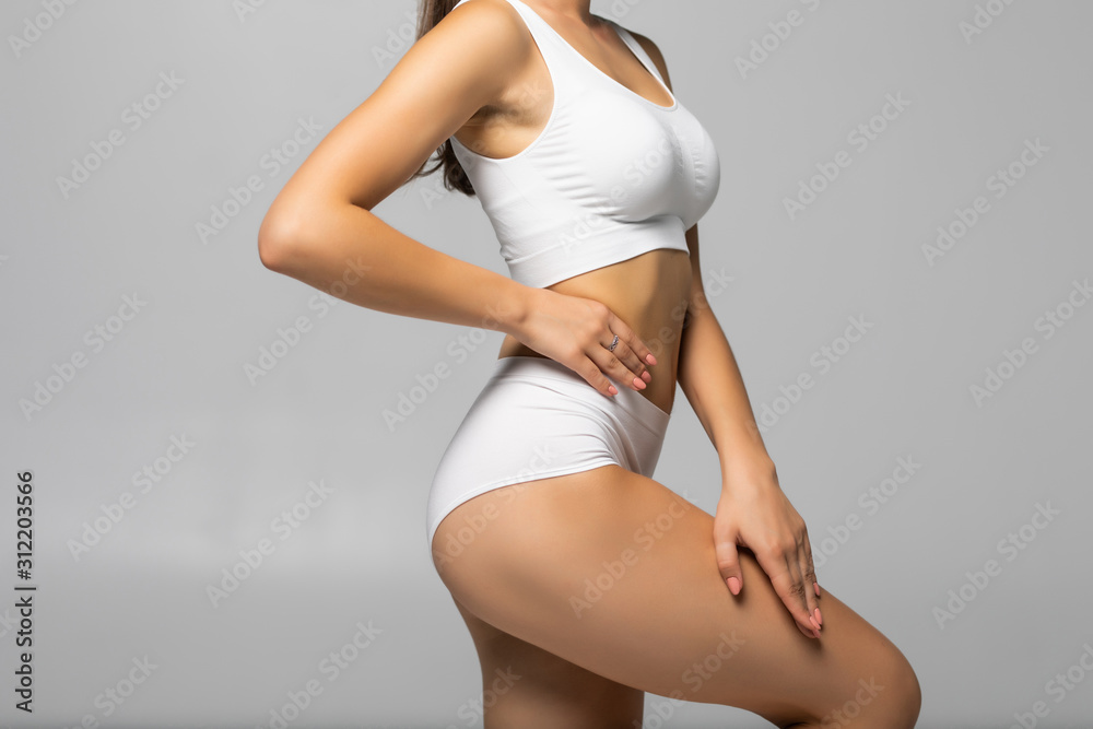 Close up shot of unrecognizable fit woman in lingerie isolated on white background. Torso of slim attractive female with flat belly in white underwear. Copy space for text. - obrazy, fototapety, plakaty 
