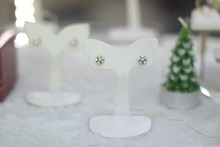 Pair Of Flower White Gold Diamond Earring In The White Display Showcase With Christmas Tree Background