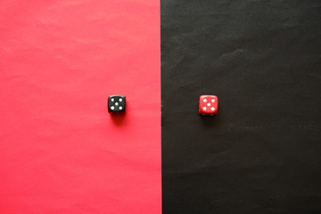 Red dice on black background and black dice on red background. Red dice shows five and black dice shows five.