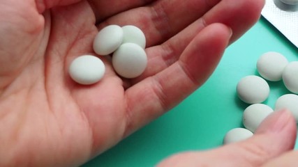 Wall Mural - The woman puts a lot of pills in the palm of her hand. The concept of overdose, medicine and health care. A dose for death. Excess of drugs in modern treatment. Capsules on a blue background