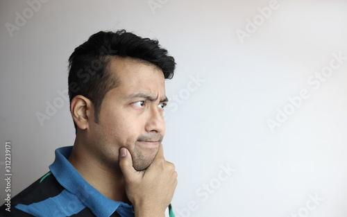 Fotomural right side face of an asian man with inquisitive expression looking towards a copy space with white background