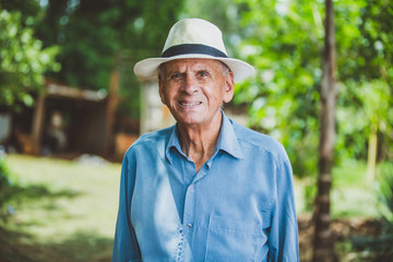 Wall Mural - Portrait of smiling beautiful older male farmer. Elderly man at farm in summer day. Gardening activity. Brazilian elderly man.