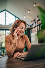 Wall Mural - Beautiful happy woman at home, looking at laptop, portrait.