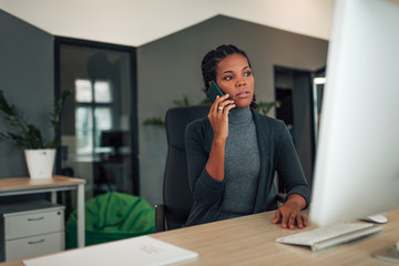 Beautiful businesswoman talking over mobile phone at modern workplace.