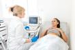 © Kate - A gynecologist sets up an ultrasound machine to diagnose a patient who is lying on a couch. A transvaginal ultrasound scanner of the internal organs of the pelvis. Female health concept