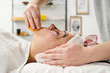 © Miljan Živković - Young woman with coffee face treatment at spa salon cosmetologist remove hold sponge mask for peeling on the face of a girl in a cosmetology room cosmetic therapy lying on bed head covered
