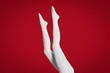 © New Africa - Woman wearing white tights on red background, closeup of legs