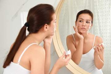 Canvas Print - Teen girl with acne problem applying cream near mirror in bathroom