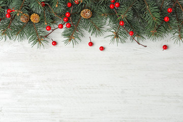 Poster - Flat lay composition with fir branches and berries on white wooden background, space for text. Winter holidays