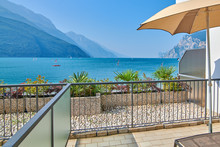 Deck Chairs On The Balcony, Lake Garda In Summer, View Of The Beautiful Lake Garda From Torbole, Surrounded By Mountains