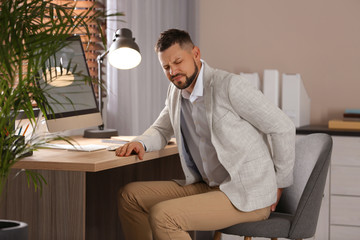 Canvas Print - Man suffering from hemorrhoid at workplace in office