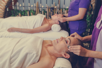 middle aged woman and young latin woman lying on massage beds in the luxurious spa, stone massage