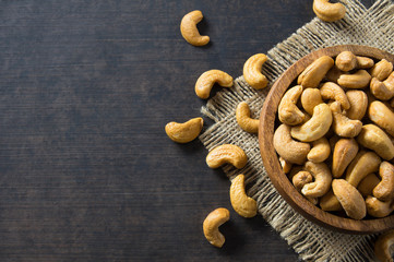 roasted salted raw cashew nuts in wooden bowl on rustic table, healthy vegetarian snack, Anacardium occidentale