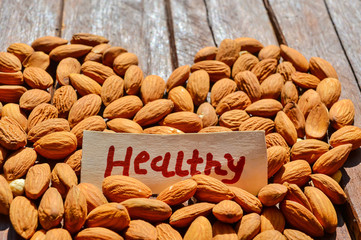 hazelnut on wooden table,almond nuts and healthy writing on wooden table,beautiful view of  healthy nuts,dry almond pile on wooden,highly nutrition raw healthy almond nut,