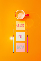 Poster - Text sign showing Click Me Now. Business photo text Internet helping desk Press the button Online Icon Nertwork Coffee cup blank colored sticky note two ballpoints clips yolk background